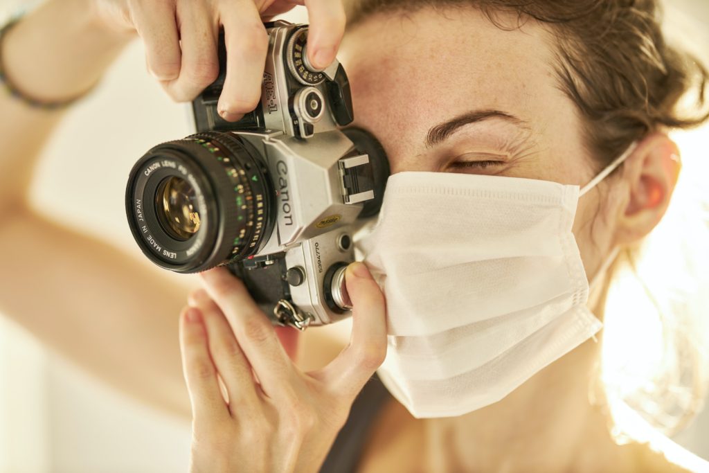 A woman taking a photo with a face mask on